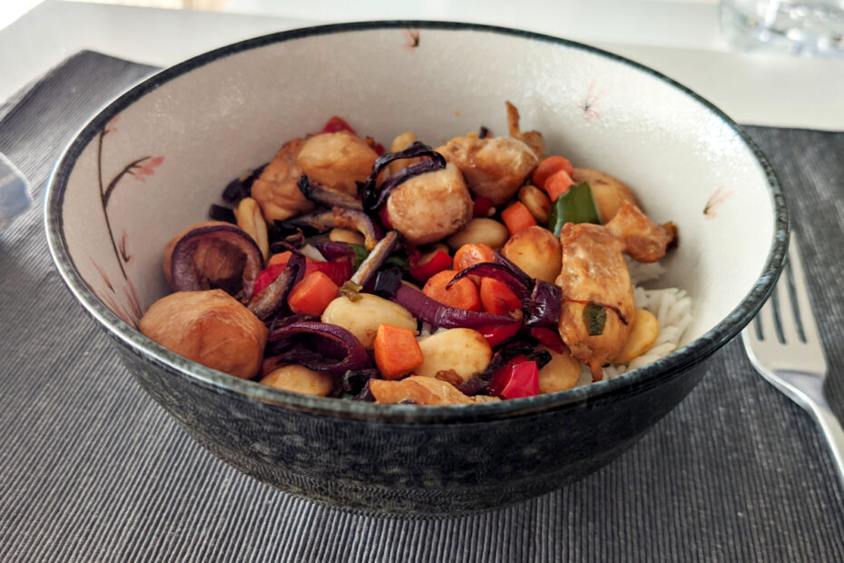 Un bol de arroz con una capa del guiso de pollo con verduras por encima