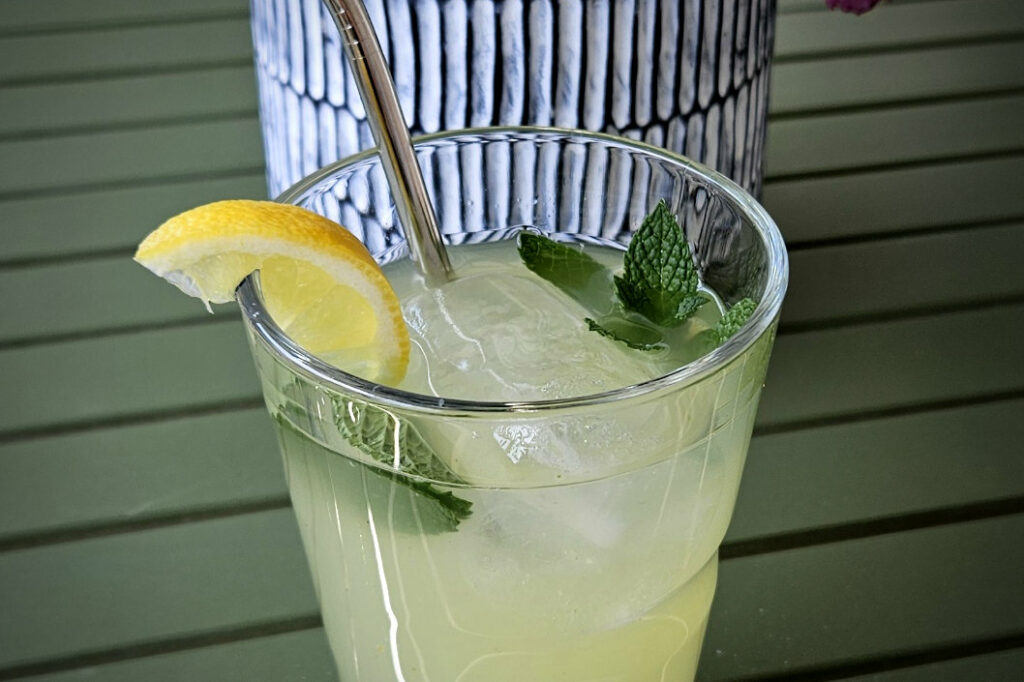 Limonada con hierbabuena, decorada con hojas de hierbabuena y una rodaja de limón.